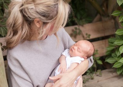 Reading and Berkshire newborn photographer, mum is holding newborn baby and looking at him in beautiful garden