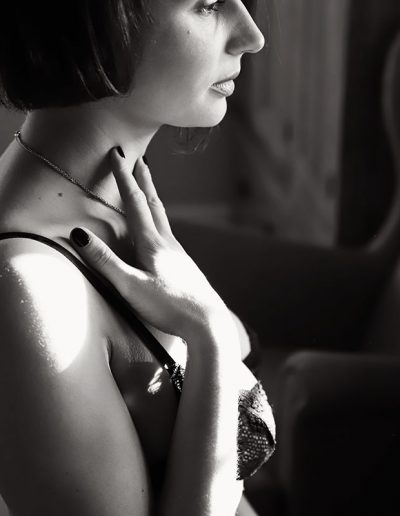 Ania chandra boudoir photographer Reading - women sitting at the makeup dest and looking at the mirror and touching her neck gently