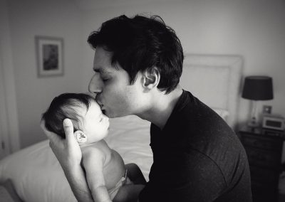 reading newborn photographer - father holding and kissing baby - ania chandra photography