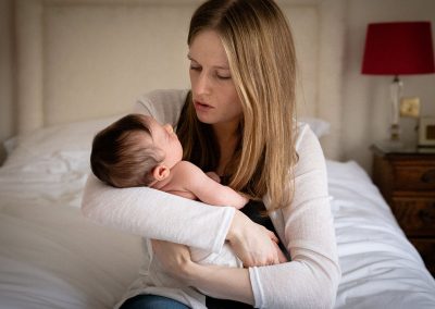 ania chandra photographer in reading - newborn photo - mum holding her san on the bed and smiling looking at him
