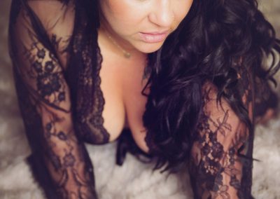 Boudoir photographer Ania Chandra in Reading - beautiful curvy women with black hair is sitting up on the bed with her hands down