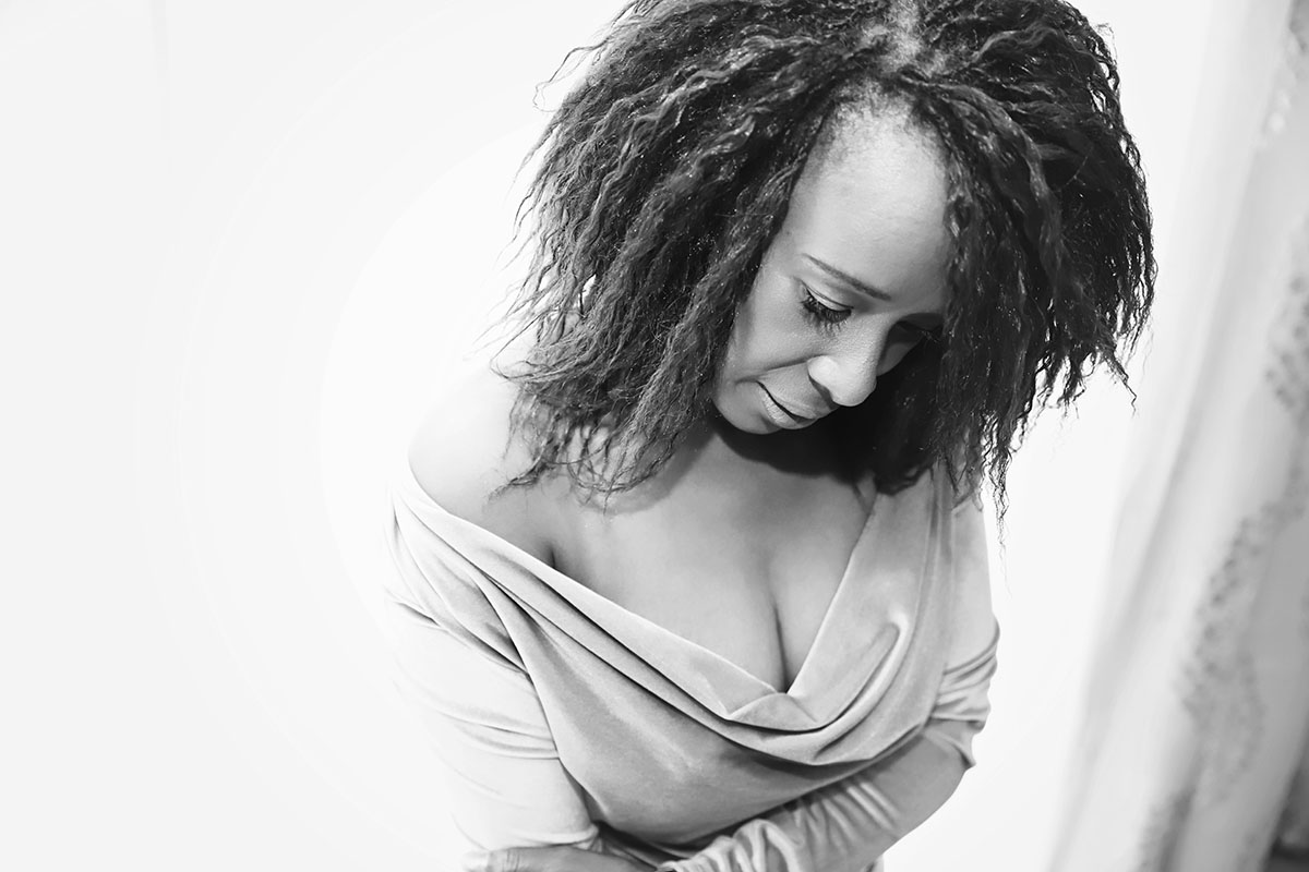 black women and a mother looking down and she has off the shoulder dress - she looks glam and elegant - Boudoir Black and White image by Ania Chandra photographer in Reading