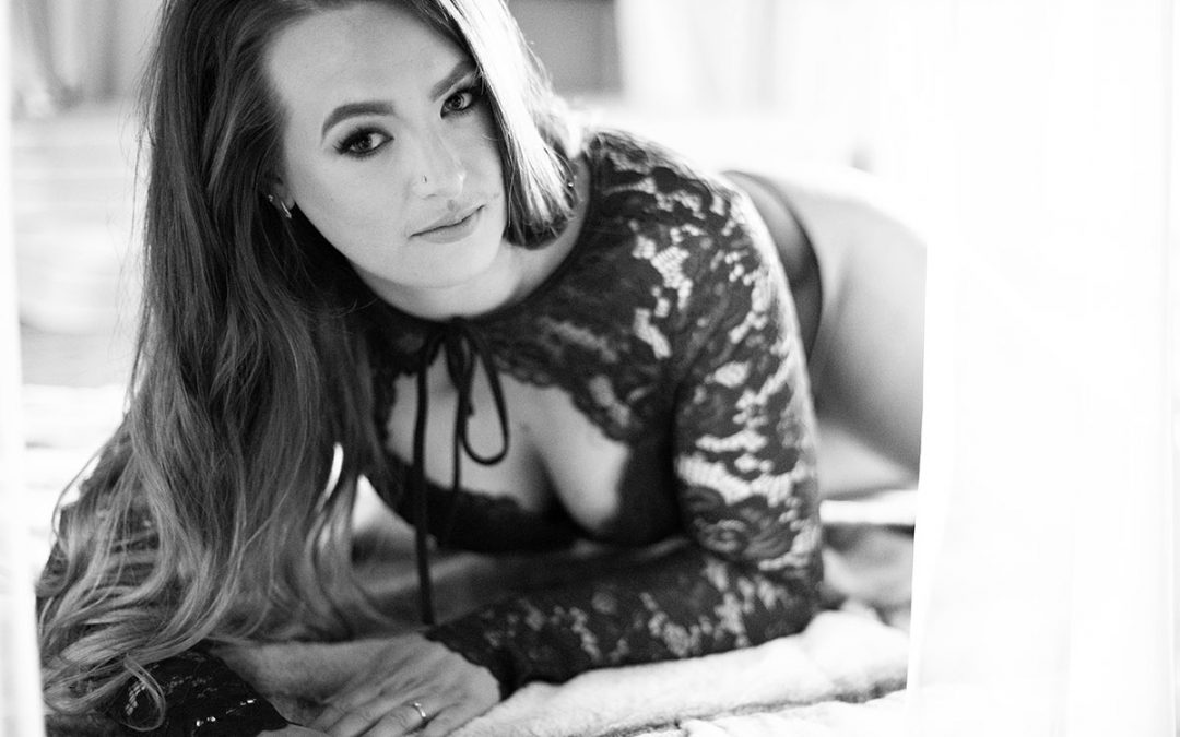 Boudoir image done by ania chandra photographer based in Reading - black and white image of a women lying down and looking at the camera in body - she has long hair and beautiful eyes